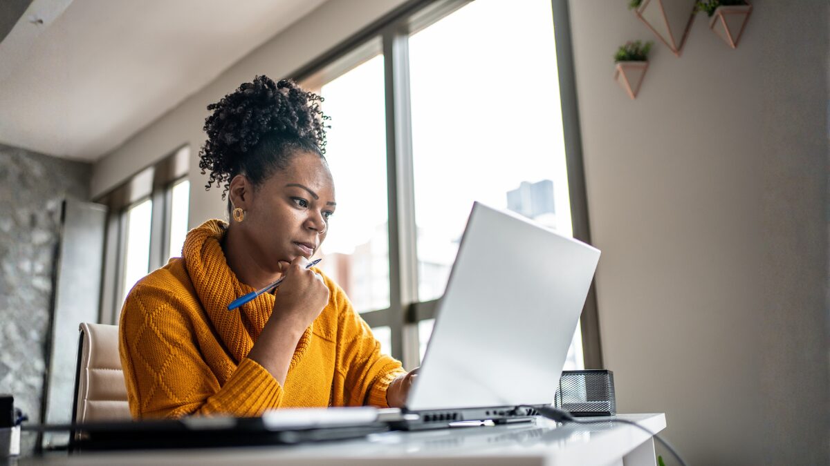 woman working at laptop wearing orange jumper